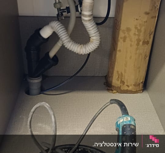 תמונה של צנרת וכלי עבודה מתחת לכיור